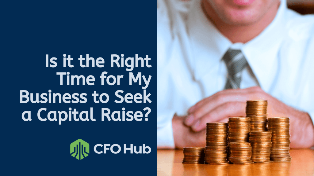 A person in business attire sits behind a table with stacks of coins. The text on the left reads, "Is it the Right Time for My Business to Seek a Capital Raise?" with the CFO Hub logo displayed below.
