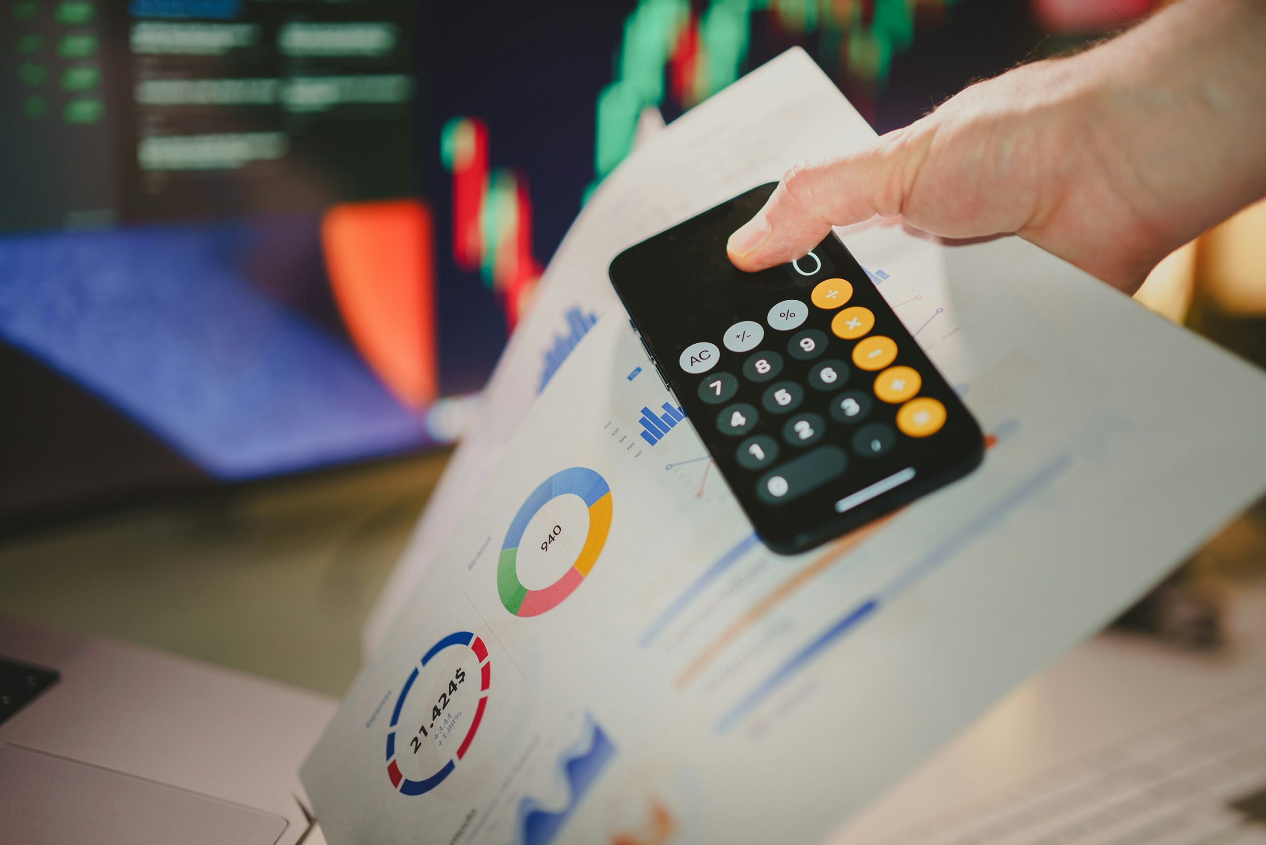 Hand holding financial reports and a calculator in an office setting