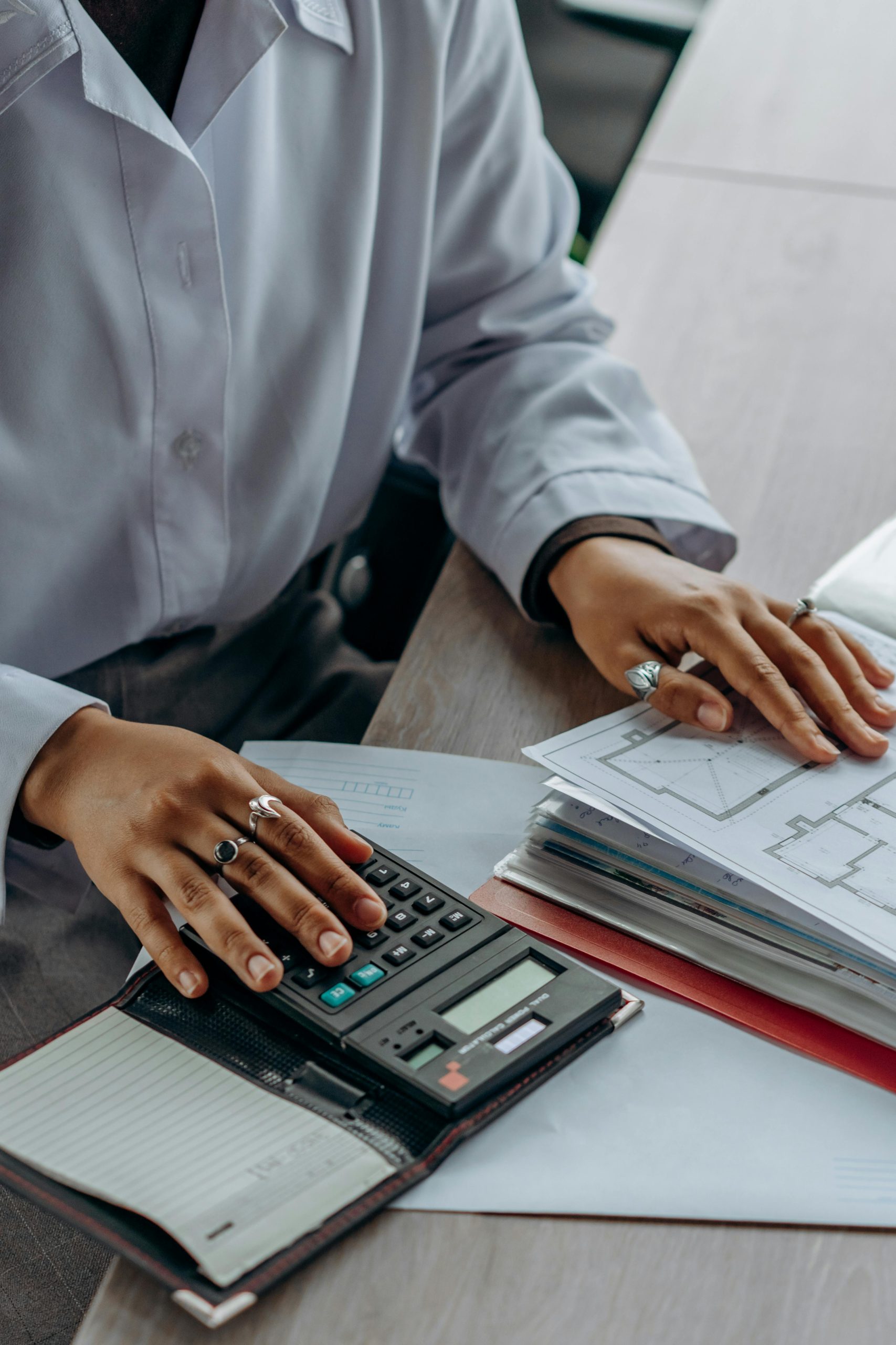 Person using a calculator and flipping through a large binder of documents