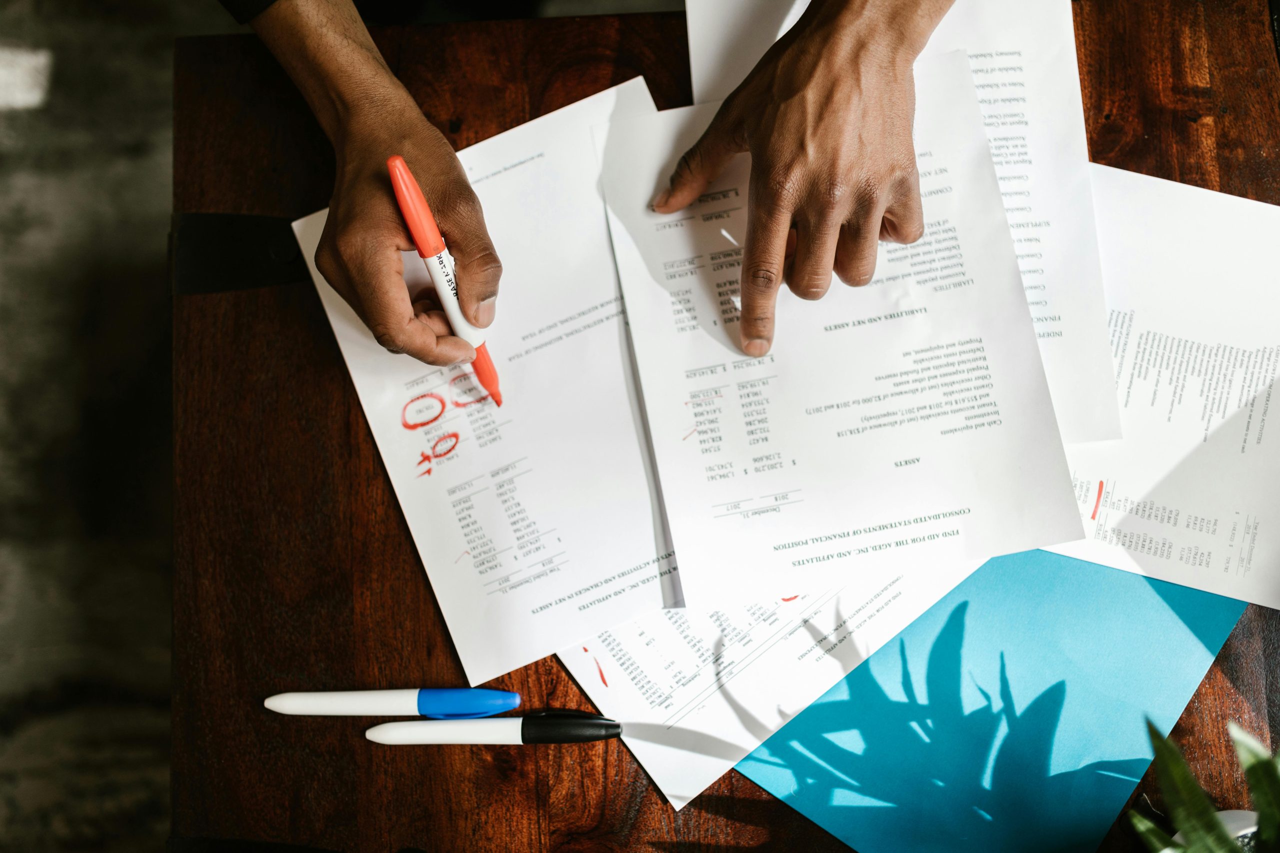 2 hands with a pen pointing at financial documents